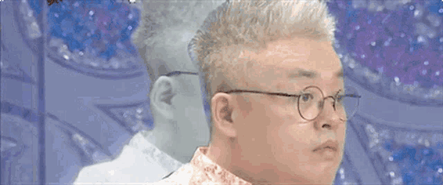 a man wearing glasses and a white shirt is looking at his reflection in a mirror .