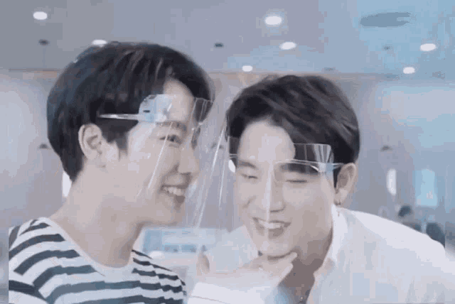 a couple of men wearing face shields are looking at each other .