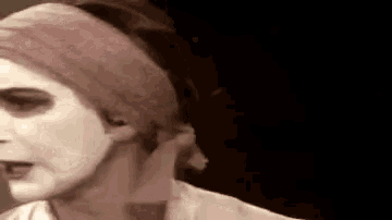 a woman with white paint on her face is wearing a headband and a scarf around her head .