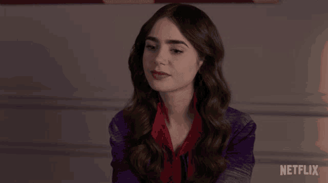 a woman in a purple jacket and red scarf is sitting in front of a netflix logo