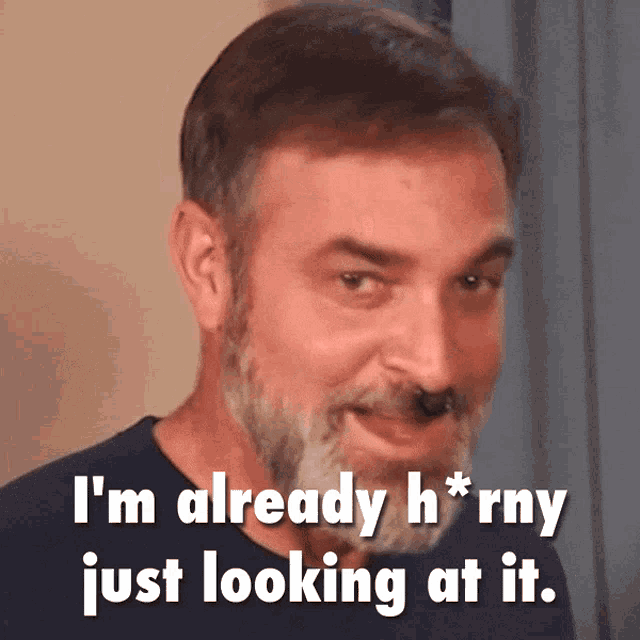 a man with a beard is smiling and says " i 'm already h * rny just looking at it "
