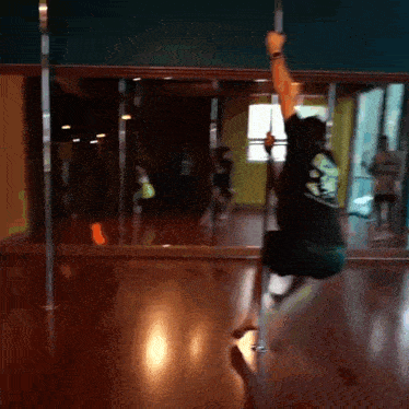 a pole dancer is doing a trick in front of a mirror in a dance studio
