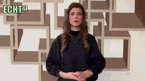 a woman in a black sweater stands in front of a wall that has echt written on it