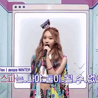 a woman is singing into a microphone while wearing a colorful dress .
