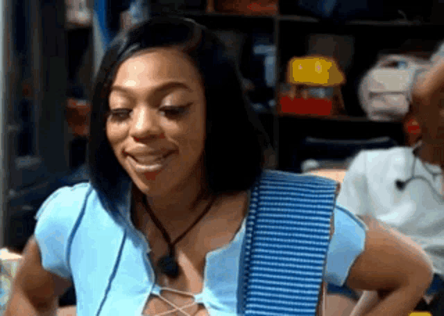 a woman in a blue shirt is smiling in front of a man in a room .