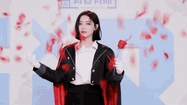 a woman in a red cape is holding a rose in front of a sign that says girl