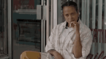 a woman is smoking a cigarette while sitting in front of a store .