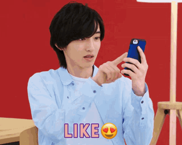 a man is holding a cell phone and the word like is on the shirt