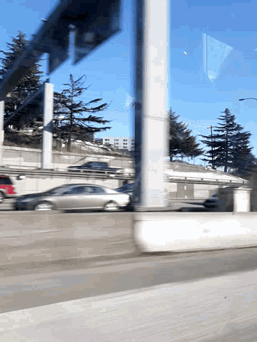 a car is driving down a highway with trees in the background and a blue sky