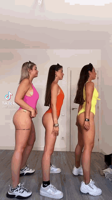 three women in swimsuits are standing next to each other in a room