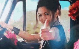 a woman is giving a thumbs up while driving a truck .