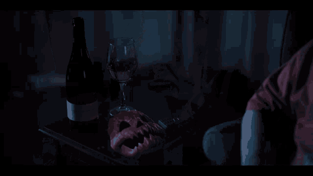 a person sitting in a dark room with a glass of wine