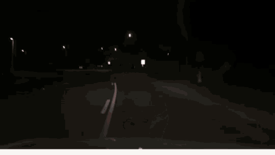 a car is driving down a road at night with the headlights on