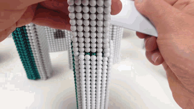 a person holds a piece of paper over a row of white beads