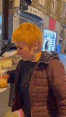 a woman with short orange hair is standing in front of a store .