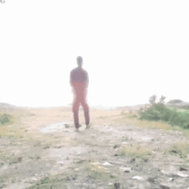 a silhouette of a man standing on top of a hill with his hand up in the air