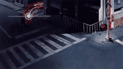 a red car is driving down a street at night with a crosswalk .
