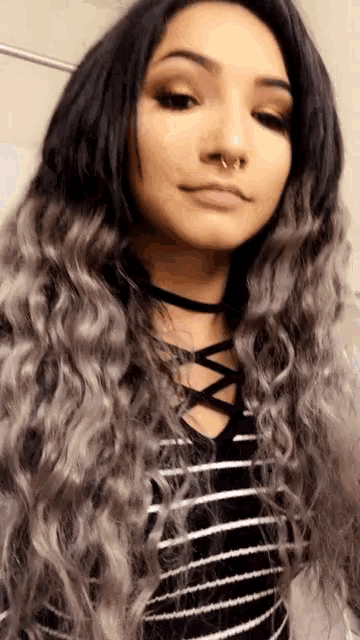 a woman with gray hair is wearing a choker and has a nose ring