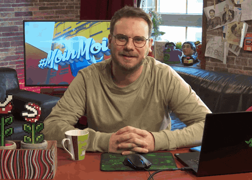 a man sitting at a desk with a sign that says #moin moi in the background