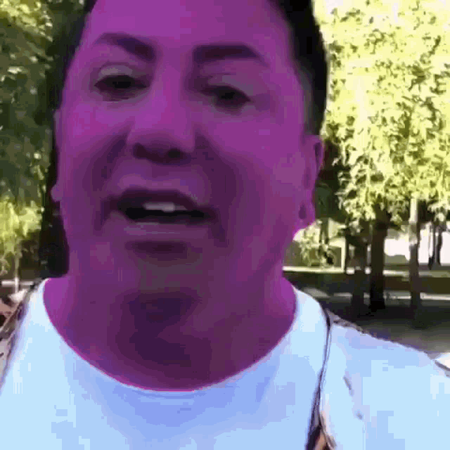 a close up of a man 's face with a purple background and trees in the background