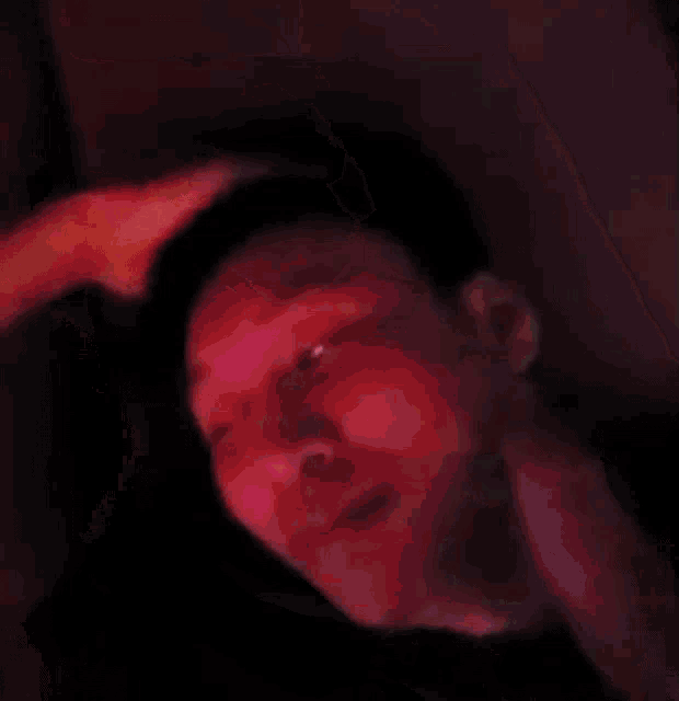 a close up of a person 's face with their eyes closed and a hand on their forehead