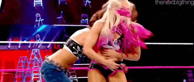 two women are wrestling in a ring and one of them is holding the other 's waist .
