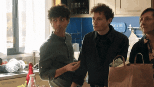 a group of people are standing in a kitchen with a sign that says ' l' eau de lait ' on it