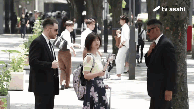 a man in a suit stands next to a woman in a floral skirt and a sign that says tv asahi