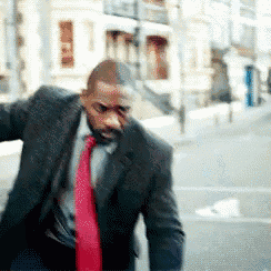 a man in a suit and red tie is walking down a street