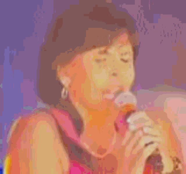 a woman singing into a microphone in front of a blue and purple background