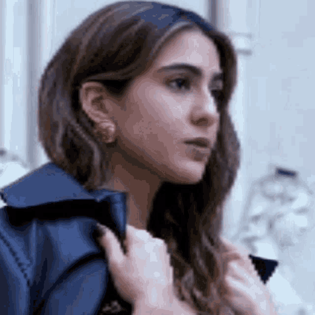a woman wearing a black jacket and earrings is holding her jacket .