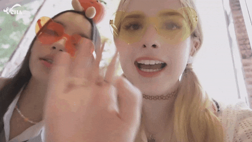 two girls wearing sunglasses and a choker are giving the middle finger