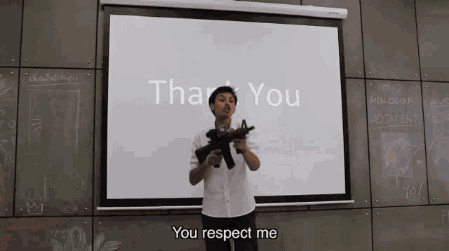 a man holding a gun in front of a white board that says thank you