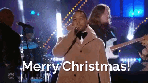 a man singing into a microphone with the words merry christmas in the background