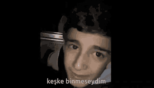 a close up of a young man 's face with a black background and the words `` keske binmeseydim '' written on it
