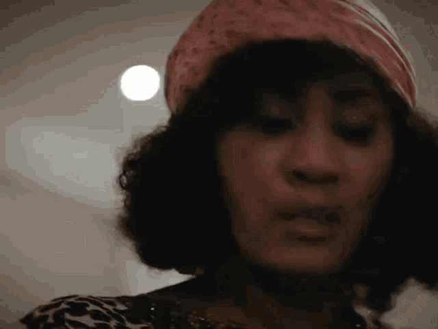 a woman wearing a pink head scarf and a leopard print dress is making a funny face .
