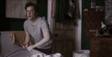 a man is standing next to a bed in a bedroom and making a bed .