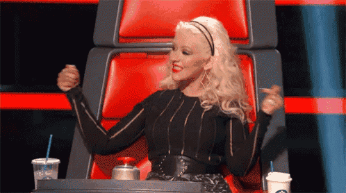 a woman is sitting in a chair with her arms in the air