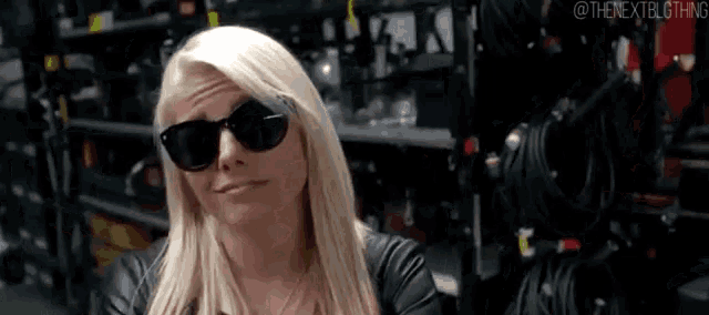 the woman is wearing sunglasses and a leather jacket .