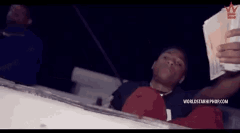 a man is laying on a boat holding a bunch of money in his hand .