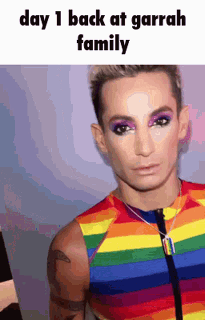 a man is wearing a rainbow shirt and has makeup on his face