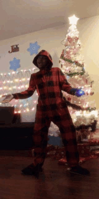 a person standing in front of a christmas tree with a star on top of it