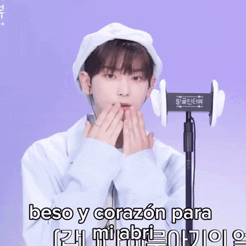 a young man wearing a white hat and ear buds says " beso y corazon para "