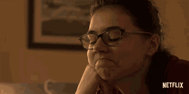 a woman wearing glasses with a netflix logo on the bottom right