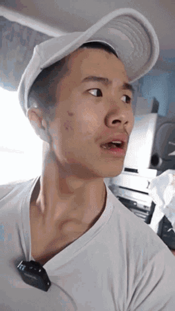 a man wearing a white hat and a t-shirt has a microphone around his neck