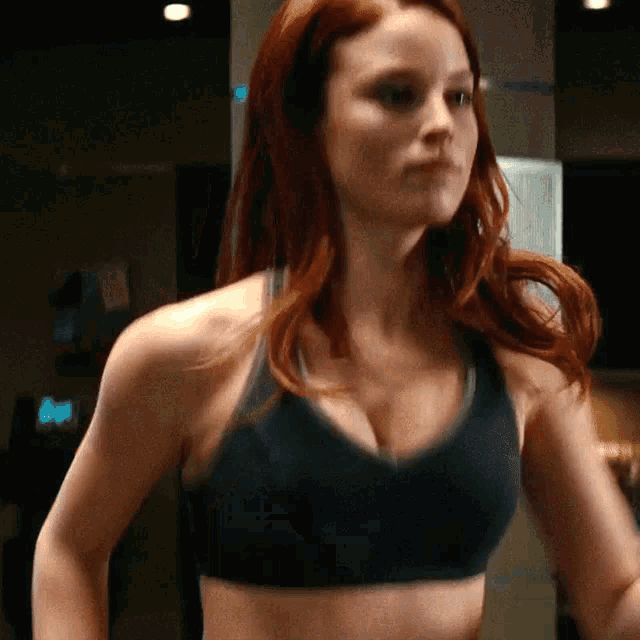 a woman in a black sports bra is standing in a dark room