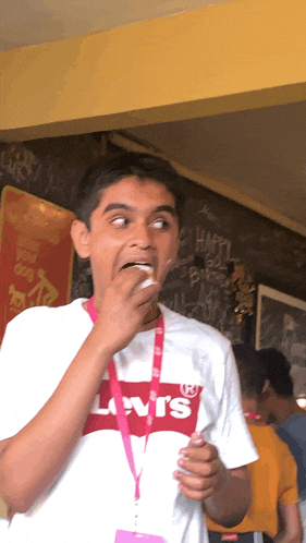 a man wearing a levi 's t-shirt eating something