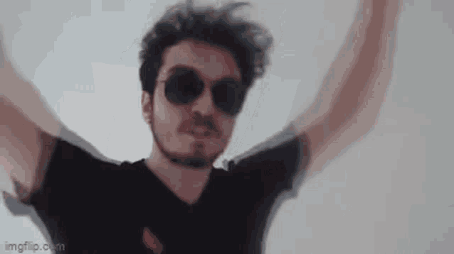 a man wearing sunglasses and a black shirt is dancing .
