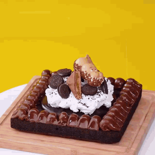 a chocolate cake with whipped cream and berries on a wooden cutting board