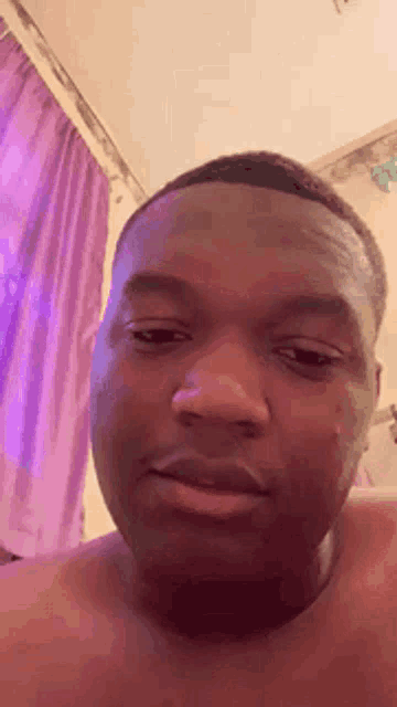 a shirtless man is making a funny face in front of a purple shower curtain .